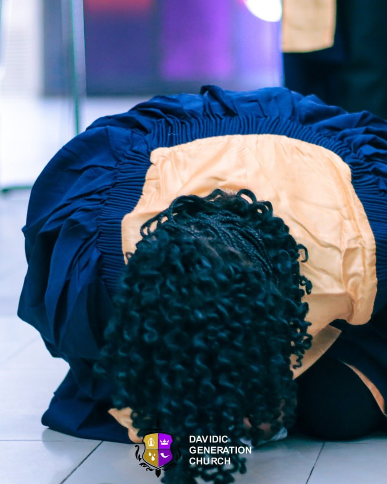 A woman kneeling in prayer during a DGC service